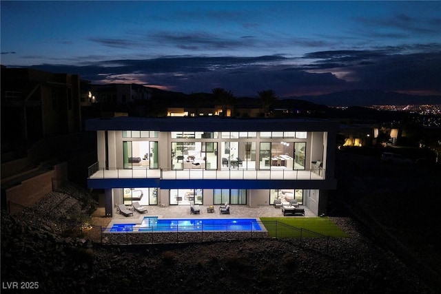 back house at dusk featuring a patio area and a balcony