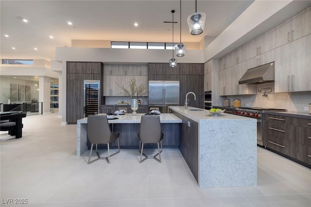 kitchen with high quality appliances, a large island, decorative light fixtures, and sink