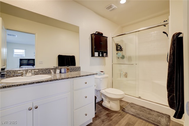 bathroom with hardwood / wood-style floors, toilet, vanity, and walk in shower