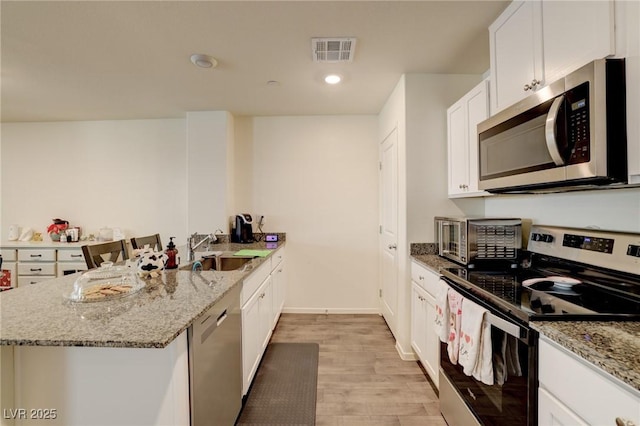 kitchen featuring appliances with stainless steel finishes, sink, light stone countertops, and white cabinets