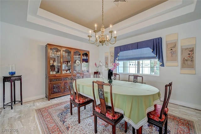 dining room with an inviting chandelier and a tray ceiling