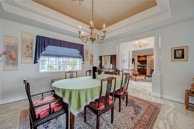 dining space with a chandelier, a raised ceiling, and decorative columns