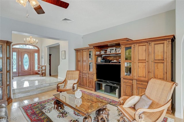 living room featuring ceiling fan with notable chandelier and light hardwood / wood-style floors