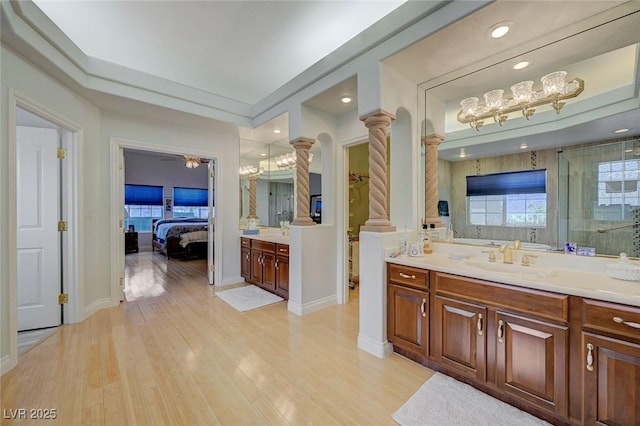 bathroom with vanity, a shower with door, decorative columns, and hardwood / wood-style floors