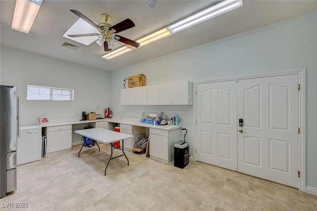 kitchen featuring ceiling fan, stainless steel fridge, and white cabinets