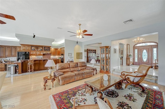 living room featuring ceiling fan with notable chandelier and light hardwood / wood-style flooring