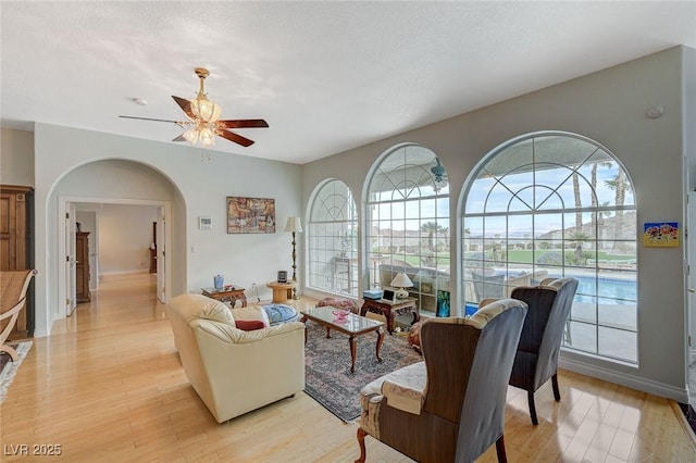 living room with ceiling fan, light hardwood / wood-style floors, a textured ceiling, and a wealth of natural light