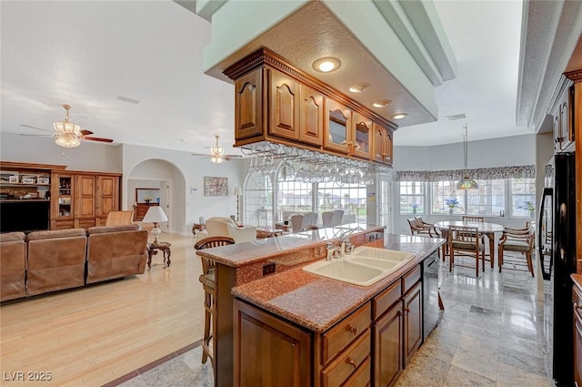 kitchen with sink, a center island with sink, stainless steel dishwasher, a kitchen breakfast bar, and pendant lighting