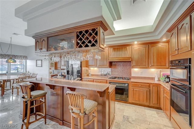 kitchen with premium range hood, appliances with stainless steel finishes, a kitchen breakfast bar, and hanging light fixtures