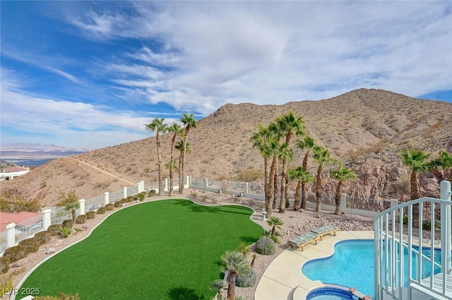 view of pool with an in ground hot tub, a mountain view, and a lawn