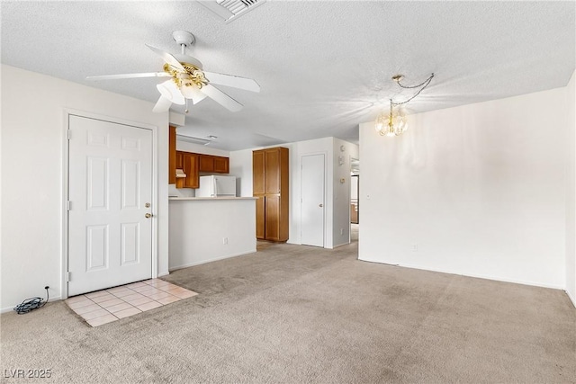 unfurnished living room with ceiling fan with notable chandelier, light colored carpet, and a textured ceiling