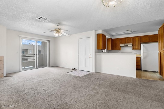 unfurnished living room with ceiling fan, light carpet, and a textured ceiling