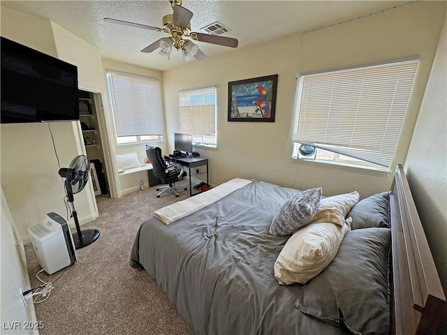 bedroom with ceiling fan, light carpet, and a textured ceiling