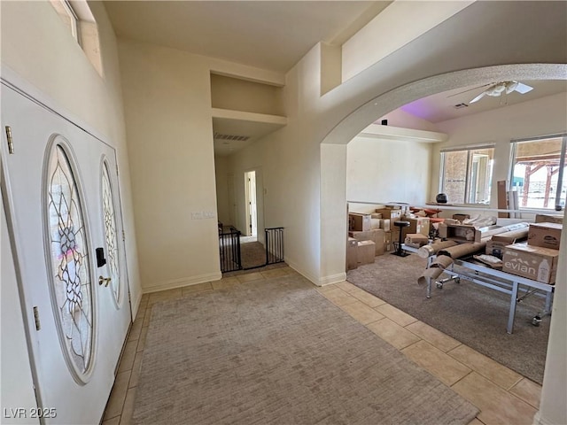 entryway with light tile patterned flooring, a towering ceiling, and ceiling fan