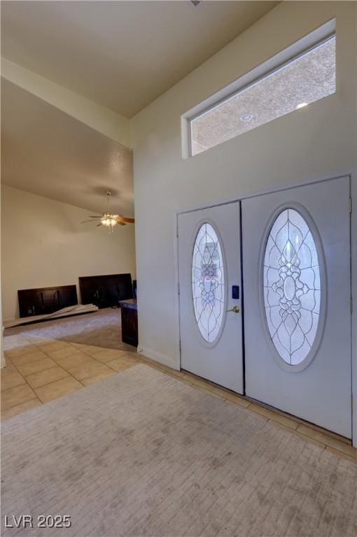 tiled foyer entrance with a towering ceiling and ceiling fan