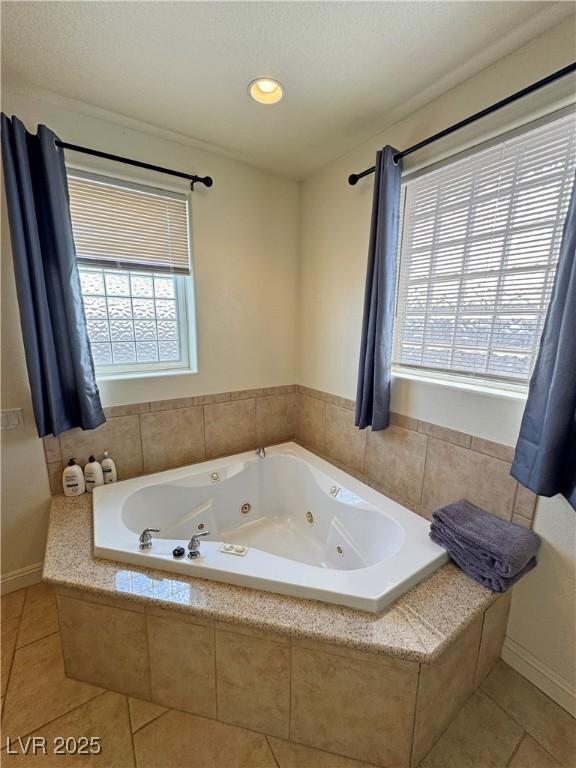 bathroom with tile patterned flooring, tiled bath, and a healthy amount of sunlight