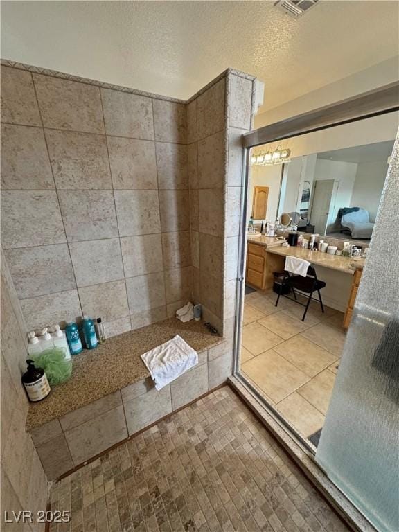 bathroom featuring vanity, a textured ceiling, and tiled shower