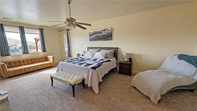 carpeted bedroom with ceiling fan and a textured ceiling