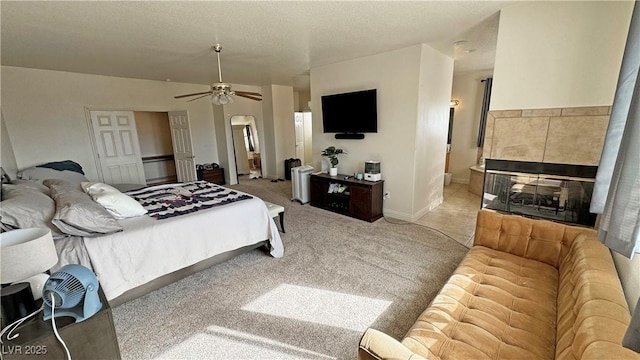 bedroom with ceiling fan, a fireplace, carpet flooring, and a textured ceiling