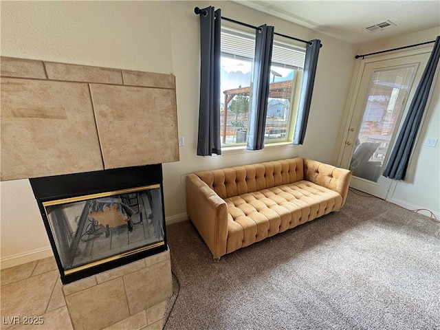 sitting room featuring a tiled fireplace and carpet flooring