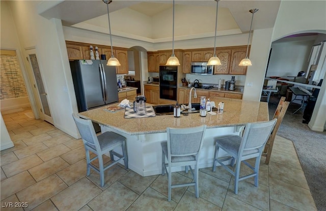 kitchen featuring appliances with stainless steel finishes, a kitchen island with sink, and hanging light fixtures