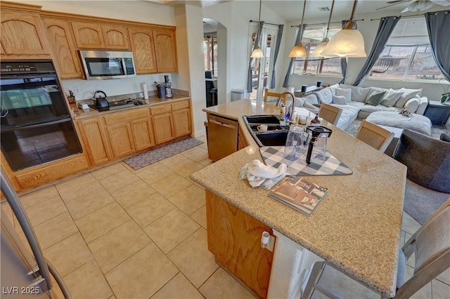 kitchen featuring hanging light fixtures, a kitchen island with sink, a kitchen breakfast bar, and black appliances