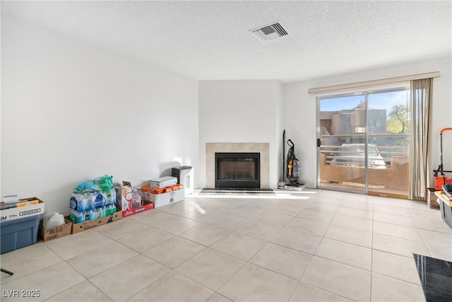 unfurnished living room with a fireplace, a textured ceiling, and light tile patterned floors