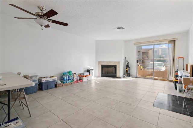 living room featuring light tile patterned flooring, ceiling fan, and a textured ceiling