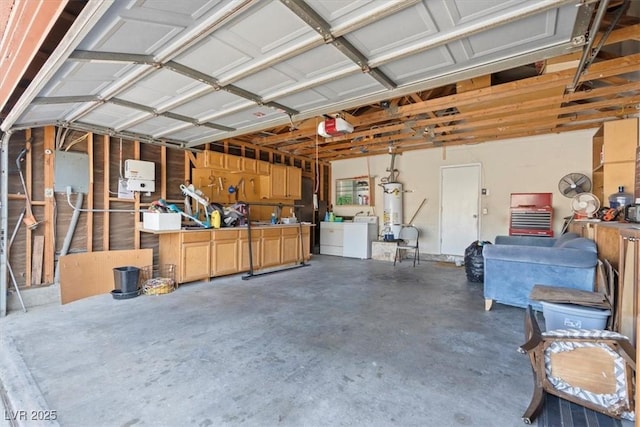 garage with washing machine and dryer, strapped water heater, and a workshop area