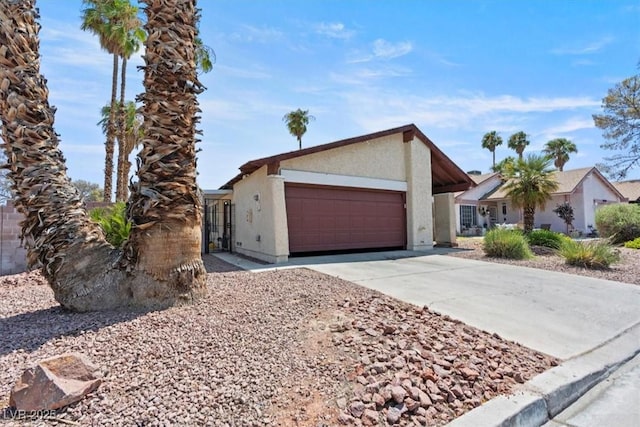 view of front facade with a garage, driveway, and stucco siding