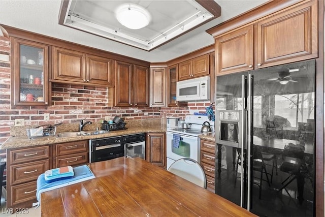 kitchen with a tray ceiling, white appliances, a sink, and glass insert cabinets