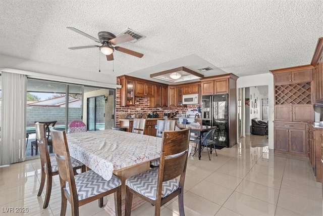 dining room with light tile patterned floors, visible vents, a textured ceiling, and a ceiling fan