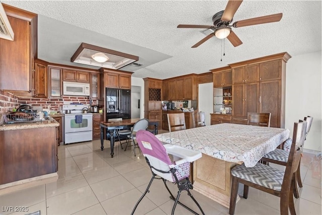 kitchen with brown cabinets, light tile patterned floors, a raised ceiling, light countertops, and white appliances