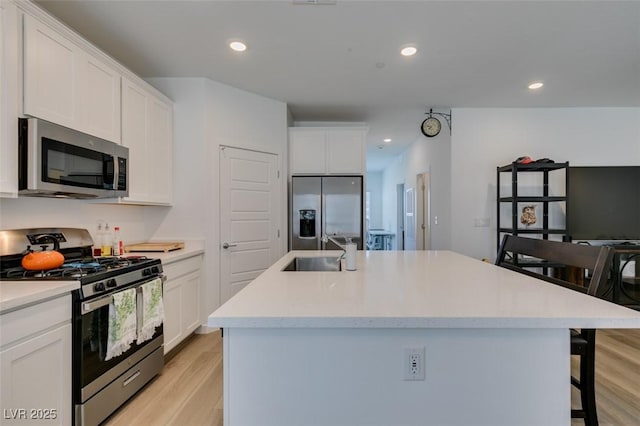 kitchen featuring white cabinetry, stainless steel appliances, sink, and an island with sink