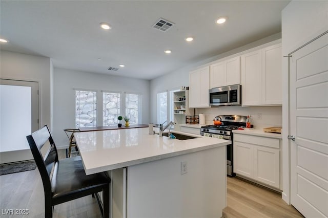 kitchen featuring a kitchen island with sink, sink, white cabinetry, and stainless steel appliances