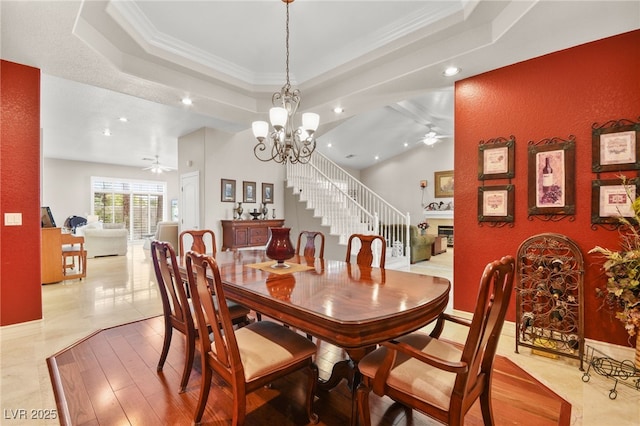 dining area featuring ornamental molding, a raised ceiling, and ceiling fan with notable chandelier