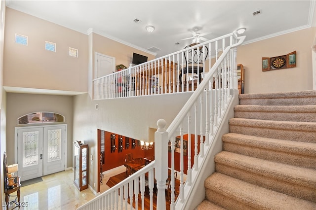 stairway featuring crown molding, a towering ceiling, ceiling fan, and french doors