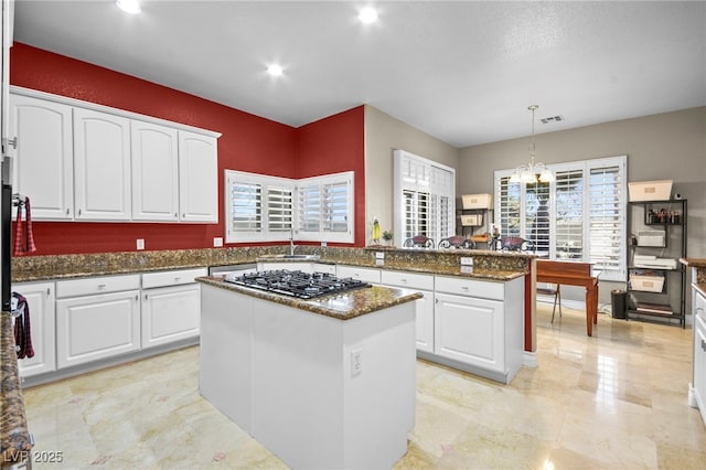 kitchen with decorative light fixtures, white cabinets, and a kitchen island