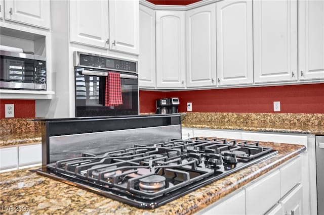 kitchen featuring dark stone counters, white cabinets, and appliances with stainless steel finishes