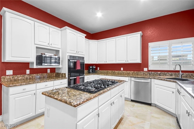 kitchen with sink, white cabinetry, dark stone countertops, a kitchen island, and black appliances