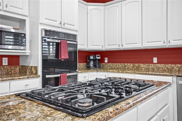 kitchen with white cabinetry, black appliances, and dark stone countertops