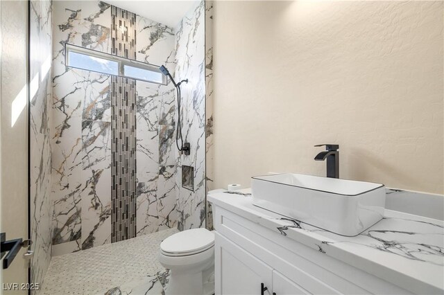 bathroom featuring vanity, a tile shower, and toilet