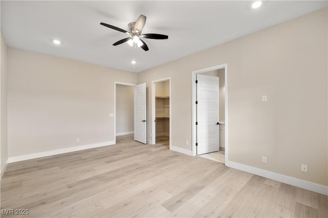 unfurnished bedroom featuring ensuite bathroom, a walk in closet, light hardwood / wood-style flooring, a closet, and ceiling fan