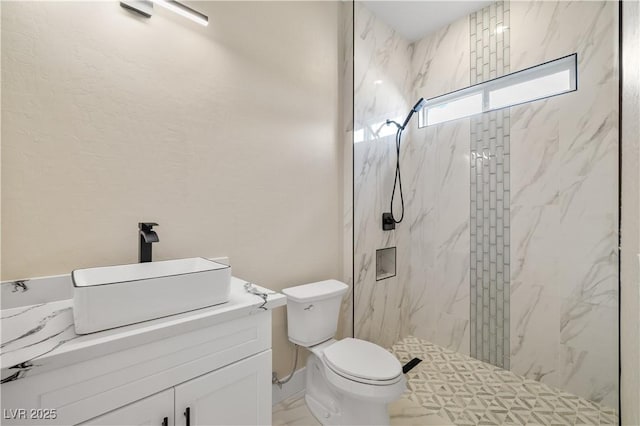 bathroom featuring tiled shower, vanity, and toilet