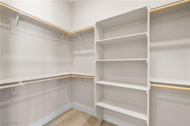 walk in closet with light hardwood / wood-style flooring