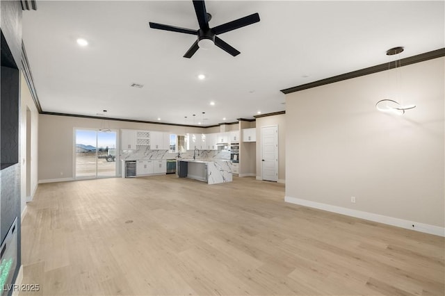 unfurnished living room with sink, wine cooler, ornamental molding, ceiling fan, and light hardwood / wood-style floors