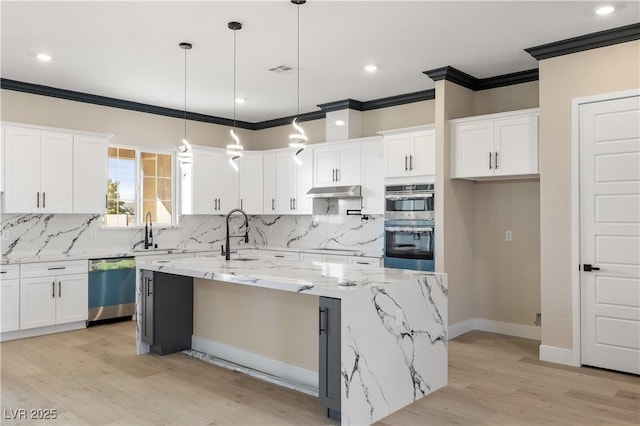 kitchen with a large island, appliances with stainless steel finishes, light stone counters, white cabinets, and decorative light fixtures