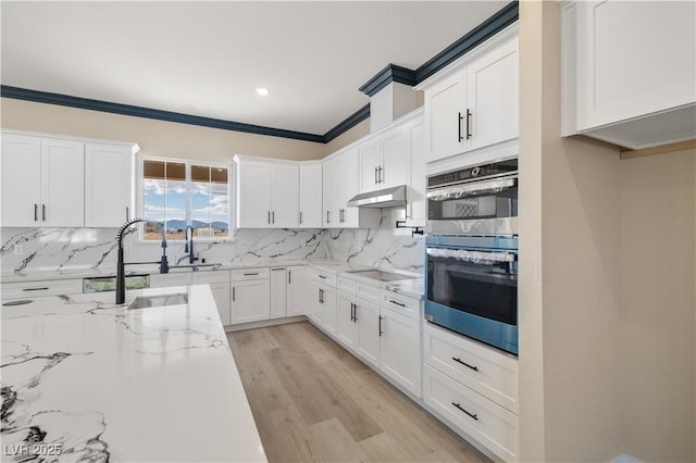 kitchen featuring double oven, light stone counters, white cabinets, decorative backsplash, and black cooktop