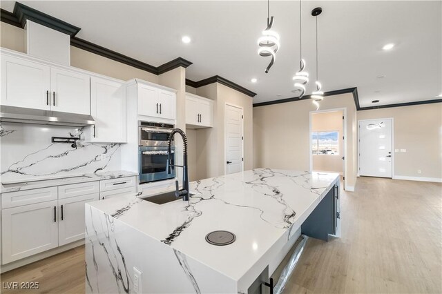 kitchen featuring pendant lighting, a kitchen island with sink, double oven, white cabinets, and cooktop