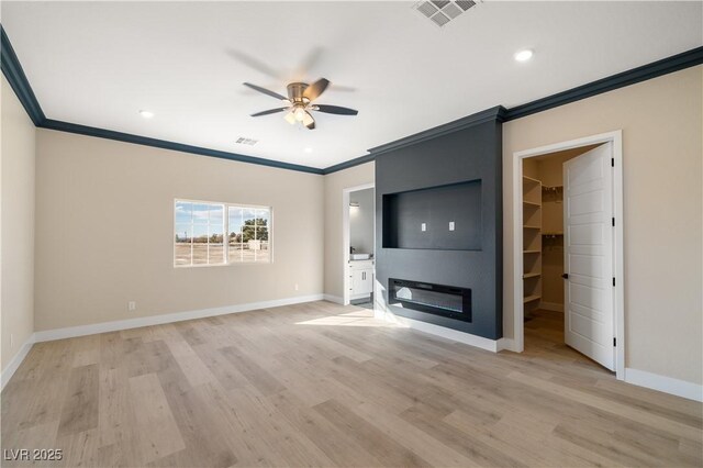 unfurnished living room with ornamental molding, light hardwood / wood-style floors, a large fireplace, and ceiling fan